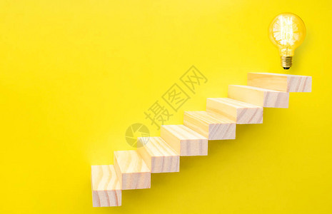 黄色背景中顶部的楼梯和灯泡图片