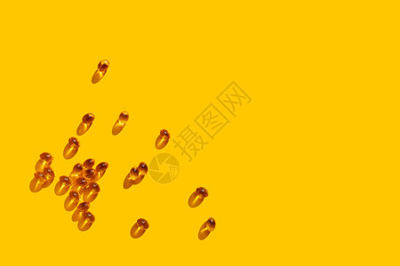 阳光下的维生素D概念在黄色背景上散布的维生素Gel图片