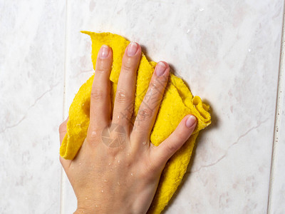 洗手间中带有黄色布和清洁用品的洗衣瓷砖图片