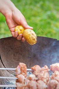 人的手在户外用火烧烤肉用烤肉串烤土豆生活方式乡村食图片
