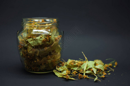 黑色背景特写的玻璃罐中的干叶和菩提花图片