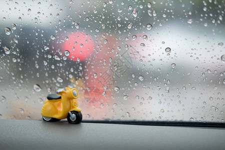 玻璃窗底有雨水滴的微型陶瓷摩托车在窗户图片