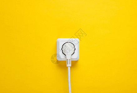 白色电缆插在黄色墙壁背景图片