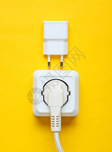 电依赖的概念插头入电源插座和黄色背景上的充图片