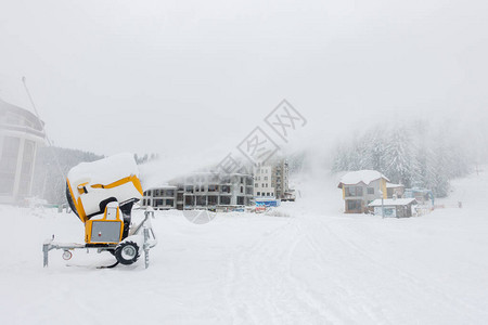 滑雪场上的移动式造雪机抽出雪背景是由于机器喷出而几乎看不到的背景图片