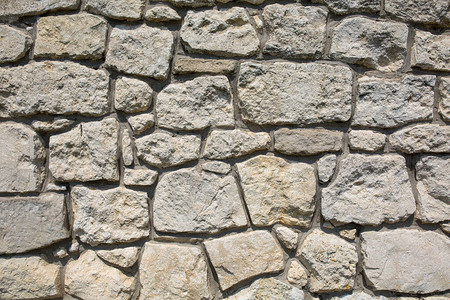 由各种灰色和黄色形状的石头组成的石墙A图片