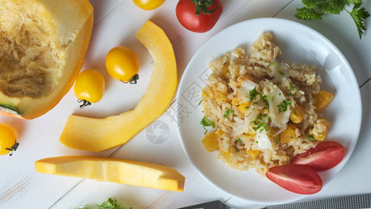 南瓜烩饭饰以新鲜欧芹和帕尔马干酪白色桌子上的意大图片