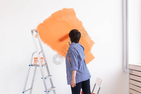 漂亮微笑的中年妇女用油漆滚筒画家的内墙图片