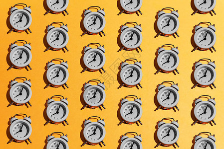 橙黄色背景上的白色复古闹钟图案创意最少的时间学校商业早晨截止日期的概念顶视图平背景图片