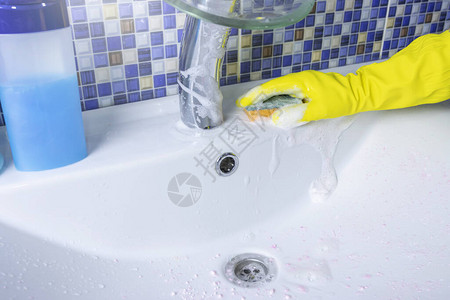 一名身着保护黄色手套的妇女用海绵和洗涤剂清洗图片