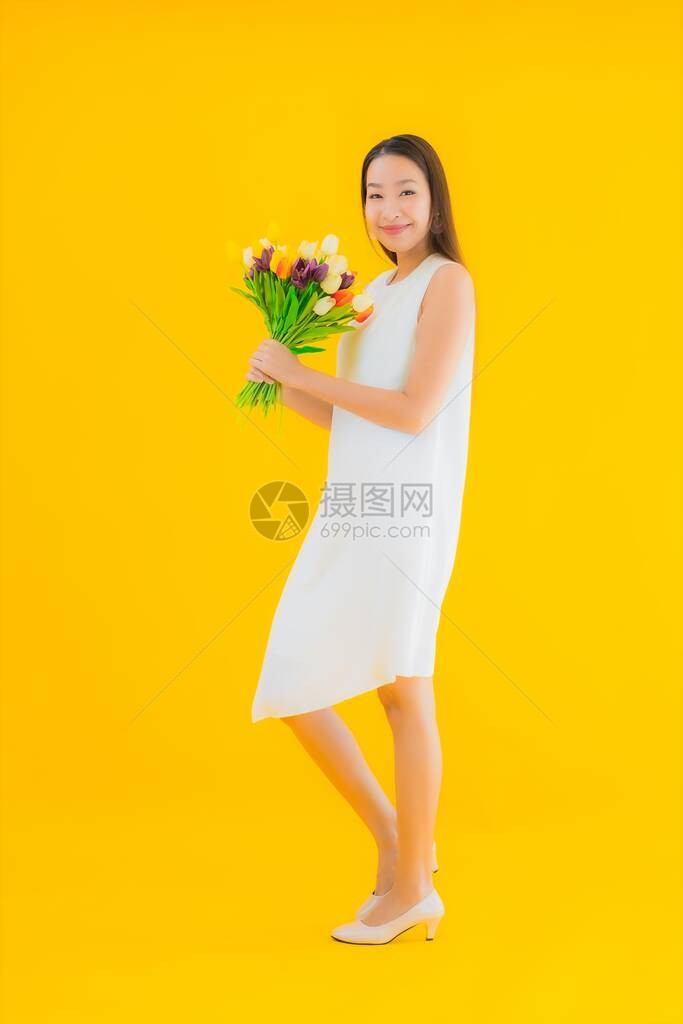 黄色孤立背景花朵的美丽年轻的年轻亚洲妇女图片