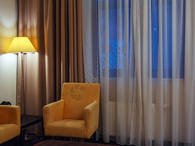 窗户旁边房间角落一盏光亮地板灯旁边的黄色扶手椅图片