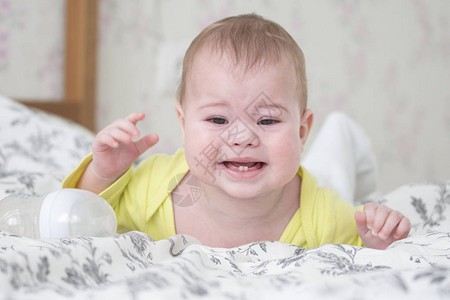67个月大的婴儿趴着哭白人男孩女小穿着黄色哭泣并展示2颗乳牙出牙背景图片