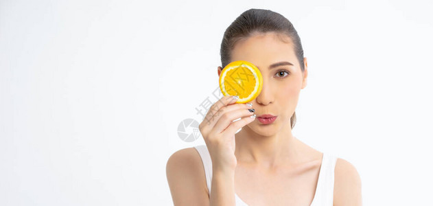 年轻漂亮的女人在她的眼前拿着一片橙子的画像图片