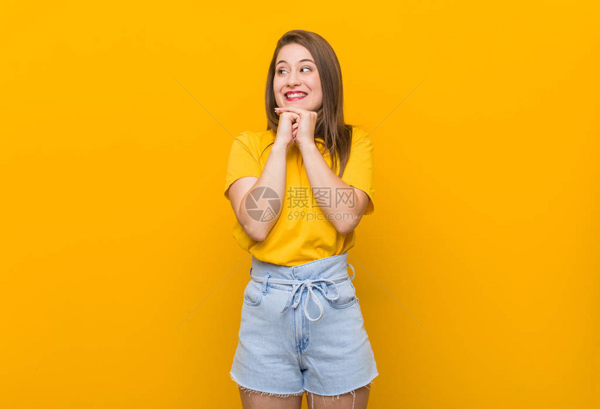 身穿黄衬衫的年轻少女将双手握在下巴并高图片