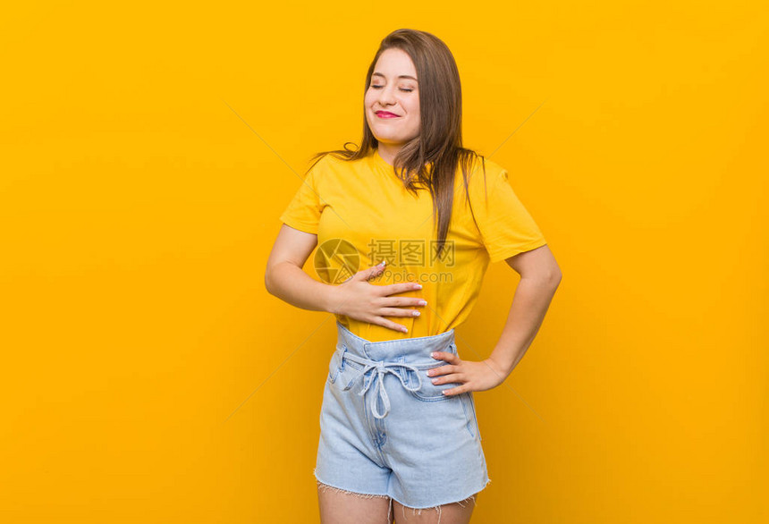 穿黄色衬衫的年轻少女触摸肚子轻笑吃饭和满足感概念图片