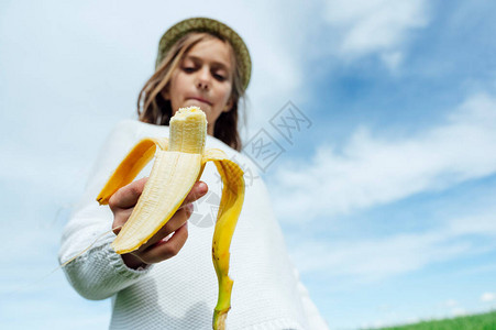 在田里吃香蕉的金发小女孩图片