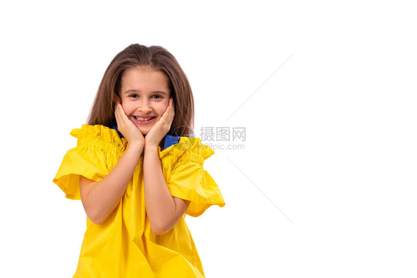 一个小女孩在白色背景上穿着黄色遮光衣的画室肖像她握图片