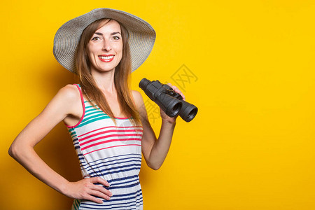 友善的年轻女子笑着带帽子和条纹裙子拿着黄色背景图片
