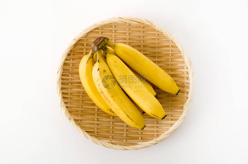 白色背景上的竹滤锅上的一堆香蕉图片