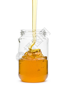 蜂蜜洒在玻璃罐里白色背景图片
