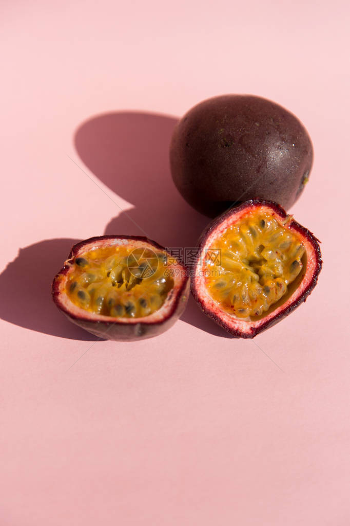 新鲜的百香果在顶部视图中以柔和的粉红色背景隔离成熟的热带百香果关闭素食的甜点间歇禁食饮图片