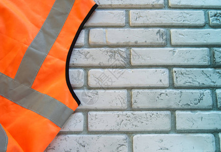 防白砖墙的橙色防弹背心的一部分背景图片
