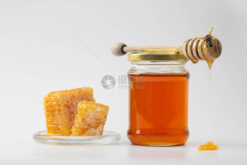 蜂蜜背景梳子里的甜蜂蜜玻璃罐中的新鲜蜂蜜蜂窝蜂蜜勺和浅色图片