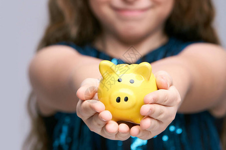 年轻女孩手中的存钱罐微笑女脸黄色存钱罐拿着有趣的小储蓄的孩子成功的图片