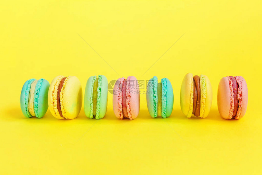甜杏仁五颜六色的独角兽粉红色蓝黄绿马卡龙或马卡龙甜点蛋糕隔离在时尚的黄色现代时尚背景法国甜饼干最小的食品烘焙概图片