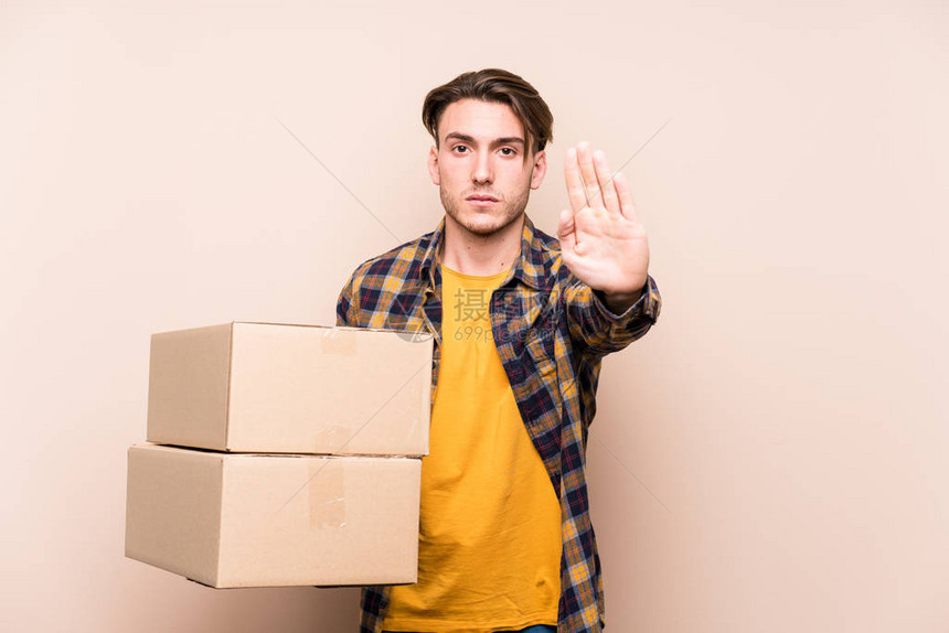 年轻的caucasian男子拿着箱子站着伸展的手显示停图片