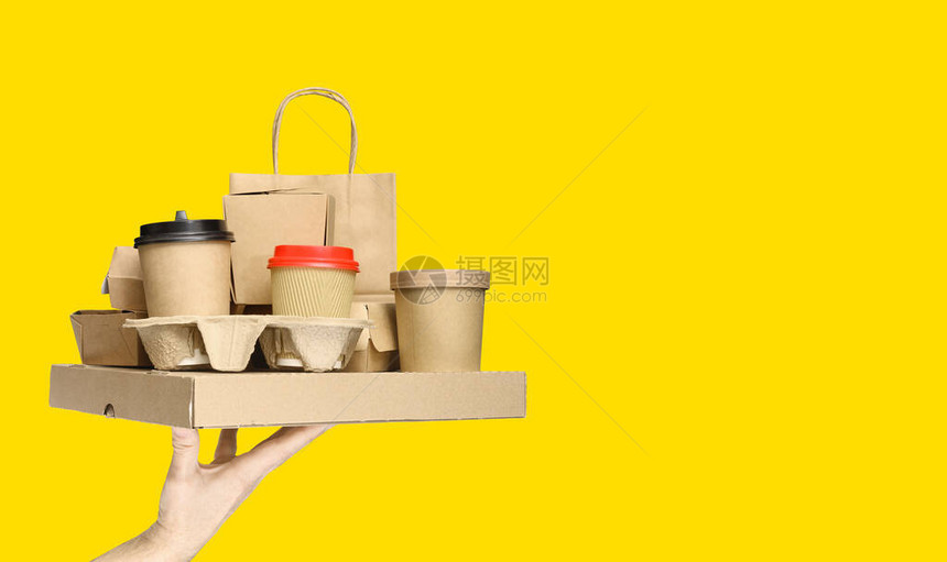 手持各种外卖食品容器披萨盒咖啡杯和黄色背景图片