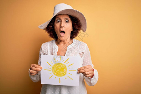 中年卷发女子在度假时拿着黄色背景上带有太阳图像的小圆面包背景图片