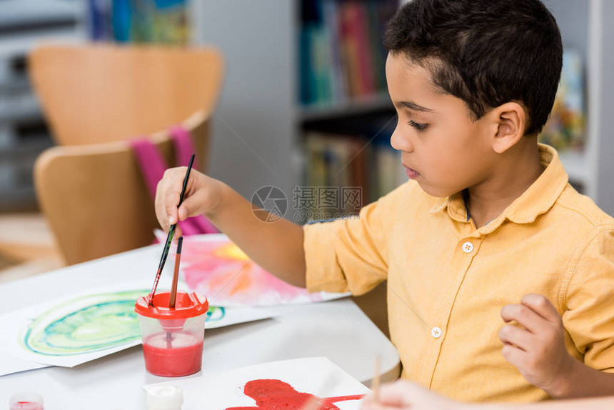 有选择焦点可爱的非裔美国小孩拿着油漆刷子在图片