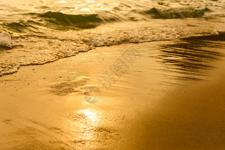 金光从海面的水浪和日落的沙子图片