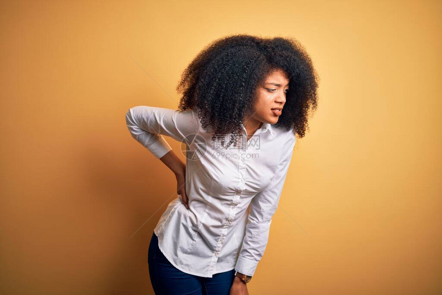 黄色背景上站立着非洲头发的年轻美丽的非洲裔美国优雅女背痛图片