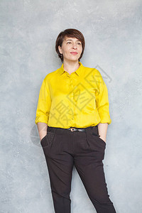 成熟的女人肖像灰色背景中身穿黄色衬衫的图片