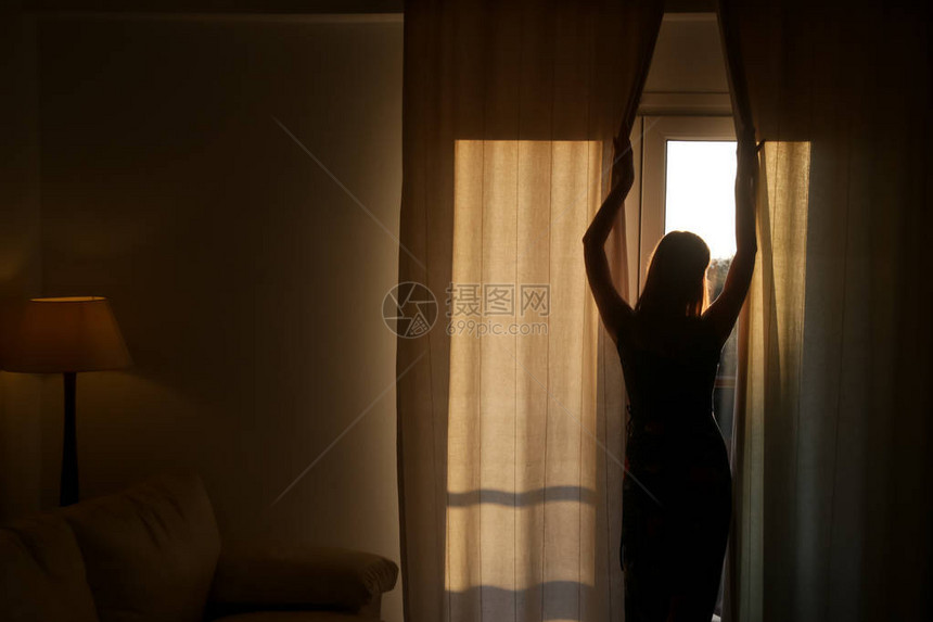 女人在一个房间开窗帘图片