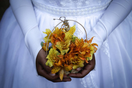 儿童手拿着带结婚戒指的花束图片