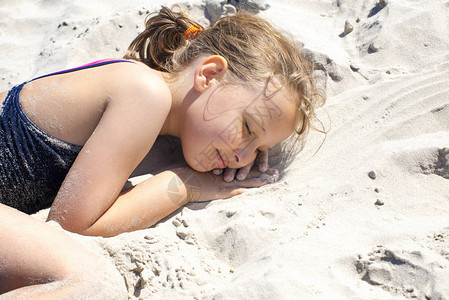 在阳光明媚的白天小女孩躺在沙图片