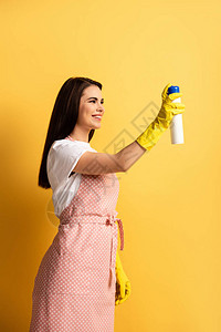 围裙和橡胶手套在黄色背景上喷图片