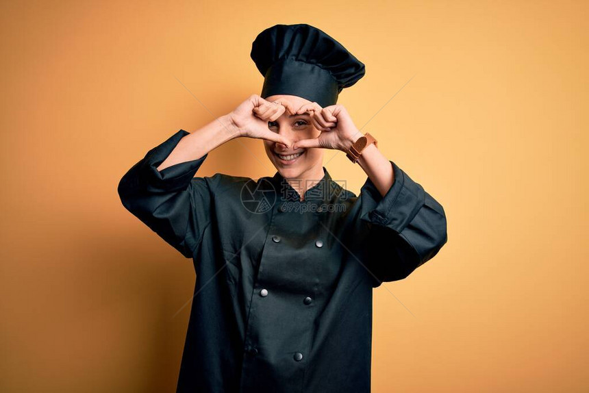 身穿炊具制服和帽子的年轻美女厨师站在黄色背景上用手和指微笑着透图片