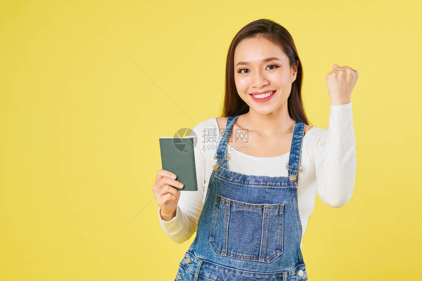 穿着牛仔服的快乐亚洲年轻女在Chenim身上总做拳头撞碰和出示护照并持签证图片