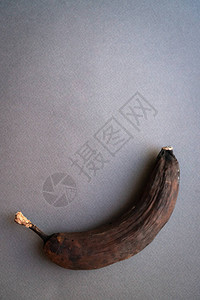 灰色背景上干燥的深棕色皮肤的老香蕉文本的地方自然老化和皮图片