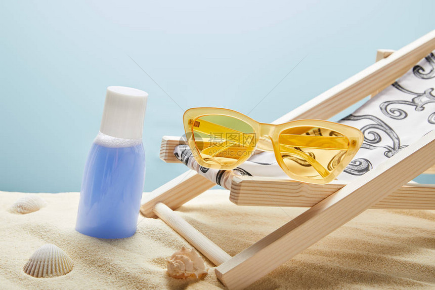 贝壳黄色太阳眼镜和蓝底甲板椅附近的沙图片