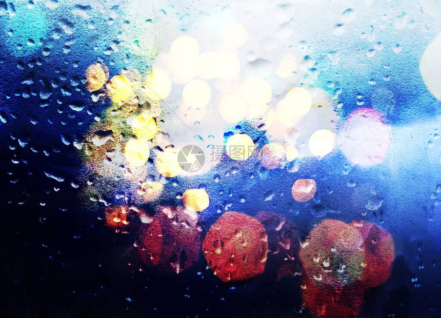 夜间城市在雨季夜晚的窗口中模糊亮光图片