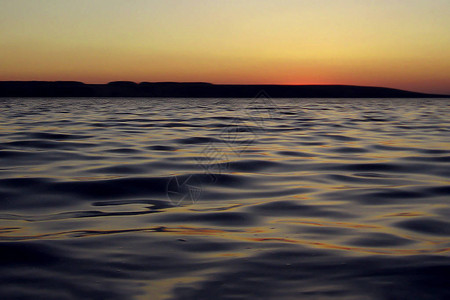 日落时水面上的波浪天快黑了背景图片