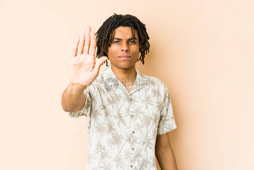 年轻的非洲美国人拉斯塔男子站在伸展的手显示停止牌图片