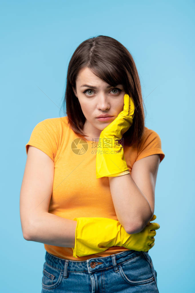身穿黄色橡皮手套和T恤衫的年青有病或心烦的年轻女图片