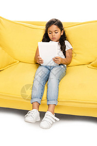 坐在黄色沙发上用数字平板电脑图片